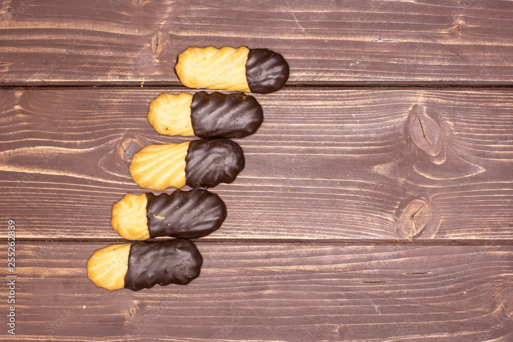 Group of five whole lazy cookie with chocolate in row flatlay on brown wood