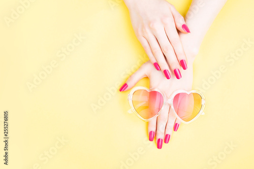 Woman hands on yellow background with sunglasses
