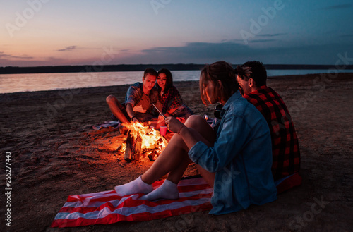 Camp on the beach. Group of young friends having picnic with bonfire