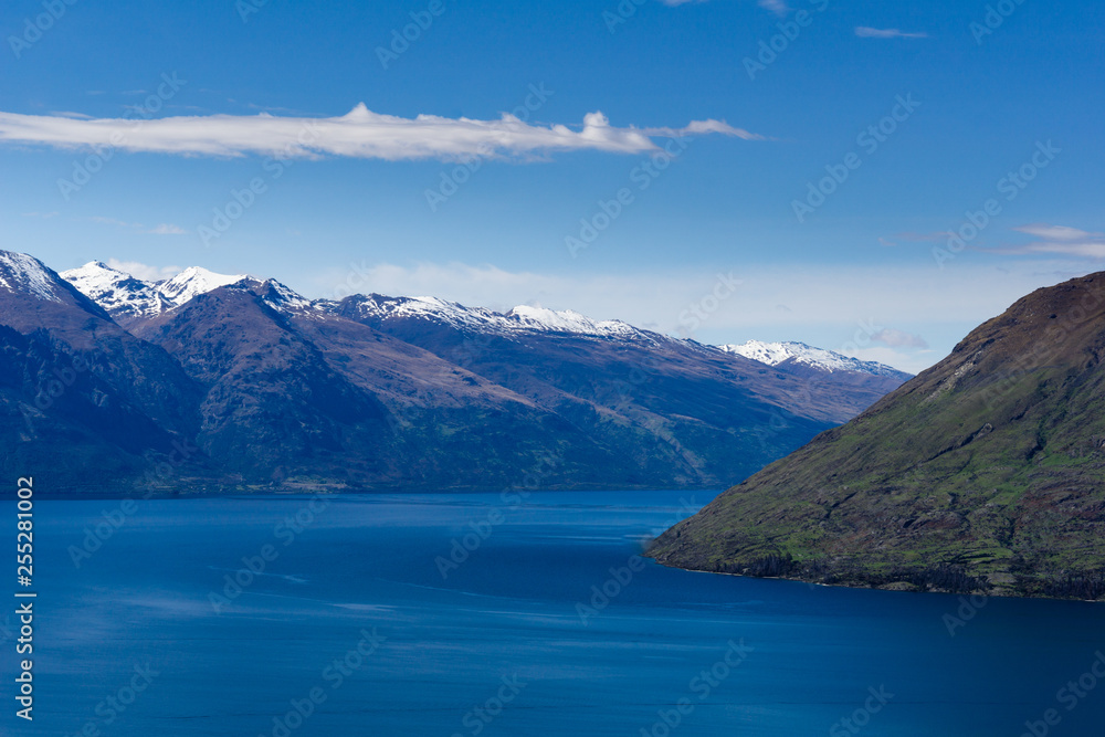 peaceful landscape during sunny day with calm sky above the lake and mountain range, perfect hiking area