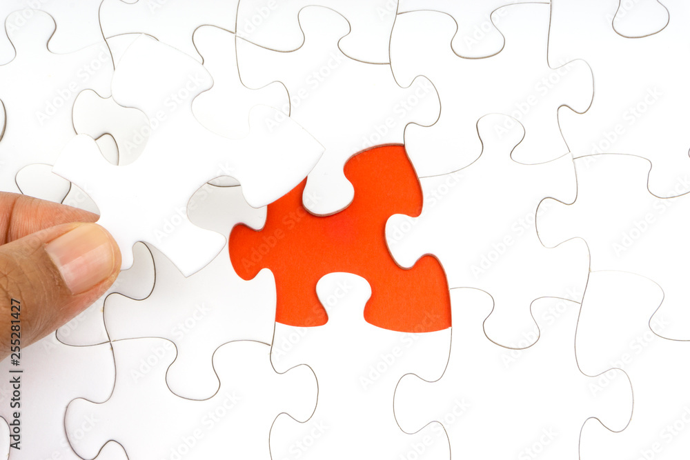 Hand put the last piece of jigsaw puzzle closeup to complete the mission. Selective focus and crop fragment Hand put the last piece of jigsaw puzzle closeup to complete the mission. Selective focus and crop fragment