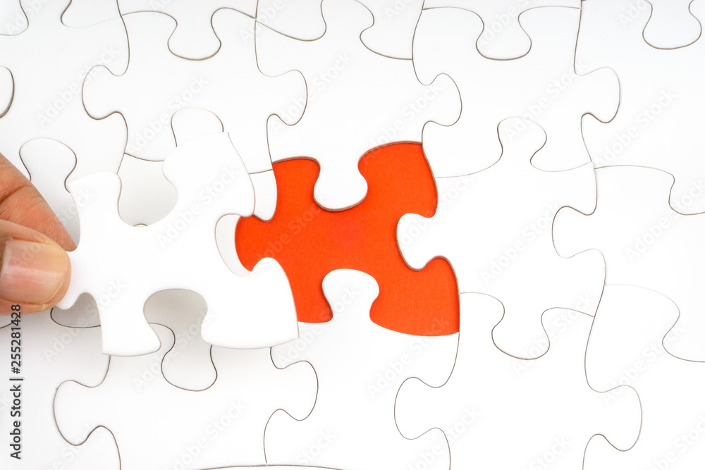 Hand put the last piece of jigsaw puzzle closeup to complete the mission. Selective focus and crop fragment Hand put the last piece of jigsaw puzzle closeup to complete the mission. Selective focus and crop fragment