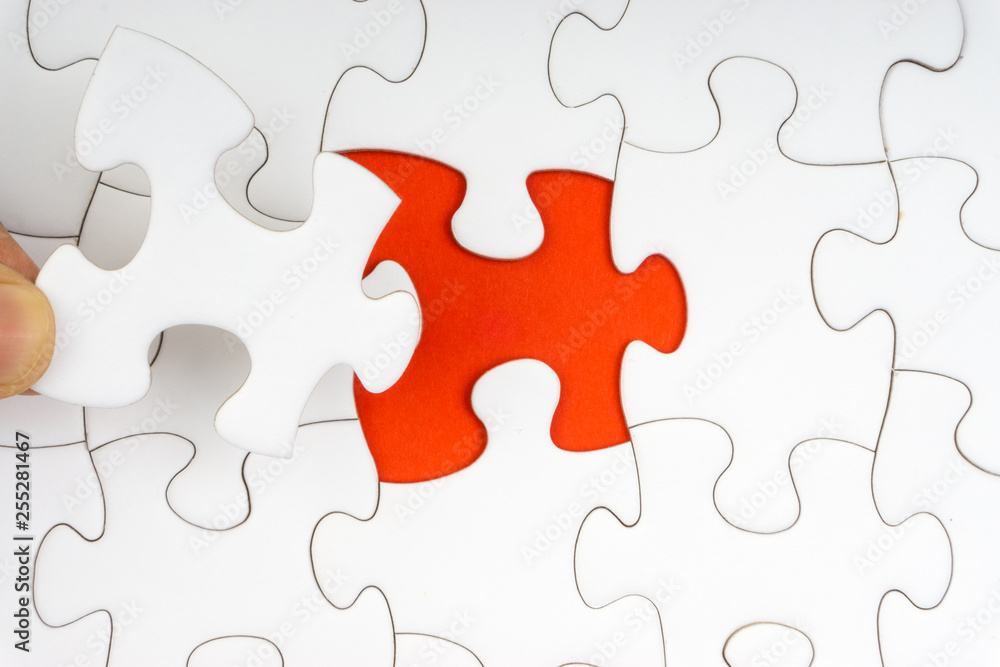 Hand put the last piece of jigsaw puzzle closeup to complete the mission. Selective focus and crop fragment Hand put the last piece of jigsaw puzzle closeup to complete the mission. Selective focus and crop fragment