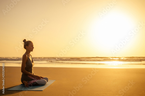 Wallpaper Mural Silhouette of young woman in a stylish suit for yogi jumpsuit doing yoga on the beach in pose copy space Torontodigital.ca