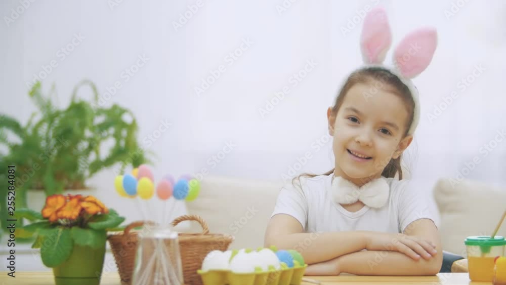 Little cute and adorable girl is smiling sincerely. Girl is pumping over, wearing bunny ears on her head. Concept Easter holiday. Little cute and adorable girl is smiling sincerely. Girl is pumping over, wearing bunny ears on her head. Concept Easter holiday.