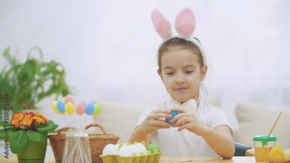 Little cute and adorable girl is smiling and playing with colorful chicken's eggs in his hands. Concept Easter holiday. Little cute and adorable girl is smiling and playing with colorful chicken's eggs in his hands. Concept Easter holiday.