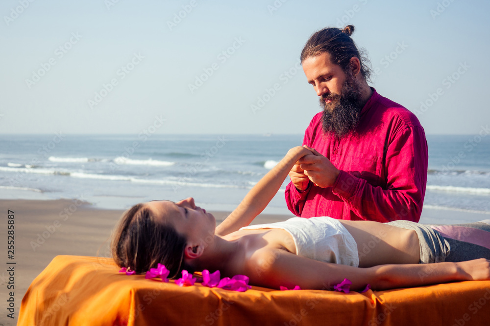 Therapeutic massage on the shore of the tropical sea. Ayurvedic relaxing massage woman in spa salon getting massage on the holiday beach.girl lying down on the table treatment procedure