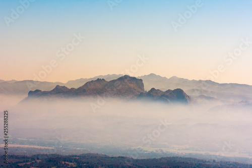 Landscape beautiful nature forest mountains and small town valley in fog with clear sky on sunrise.