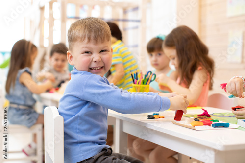 smiling kid playing with colorful clay with kindergarten group photo
