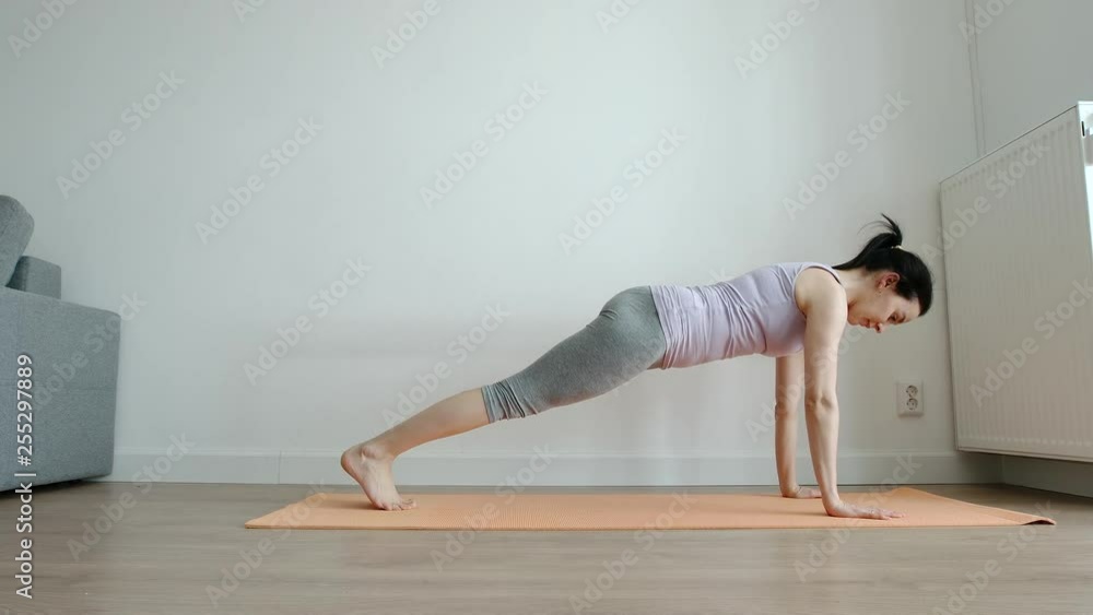 YOGA: Slim young woman practising yoga on a mat at home - Front View YOGA: Slim young woman practising yoga on a mat at home - Front View