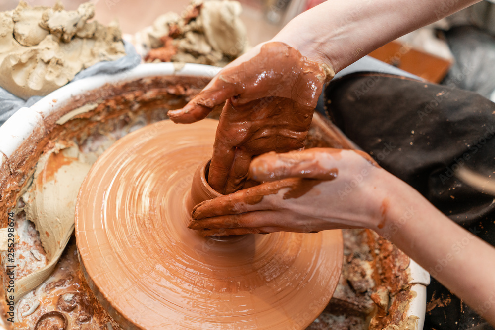 Craftsman hands making pottery bowl. Woman working on potter wheel . Family business shop sculpts pot from clay view top.
