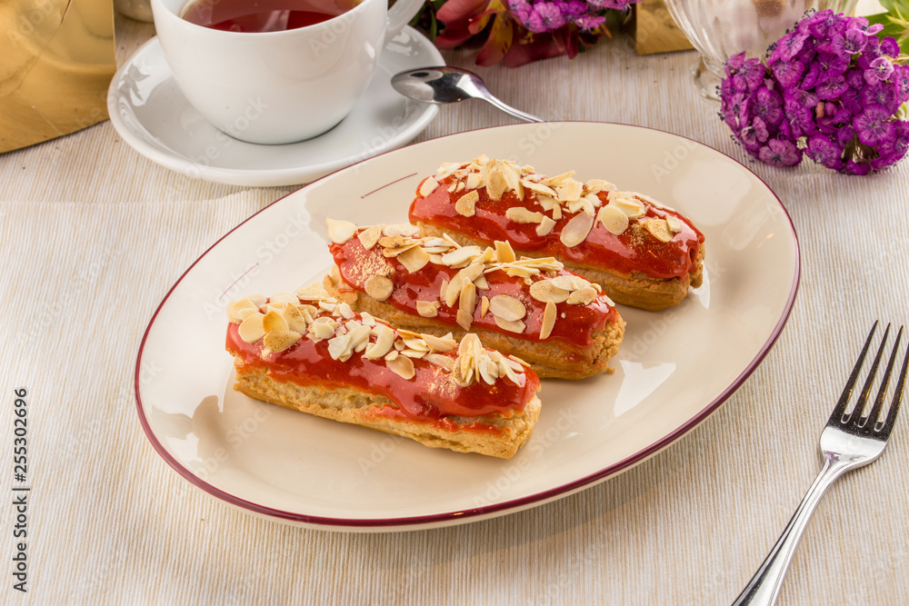 caramel almond eclairs with tea cup on textile napkin caramel almond eclairs with tea cup on textile napkin