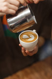 Barista pours prepared cappuccino into a cup