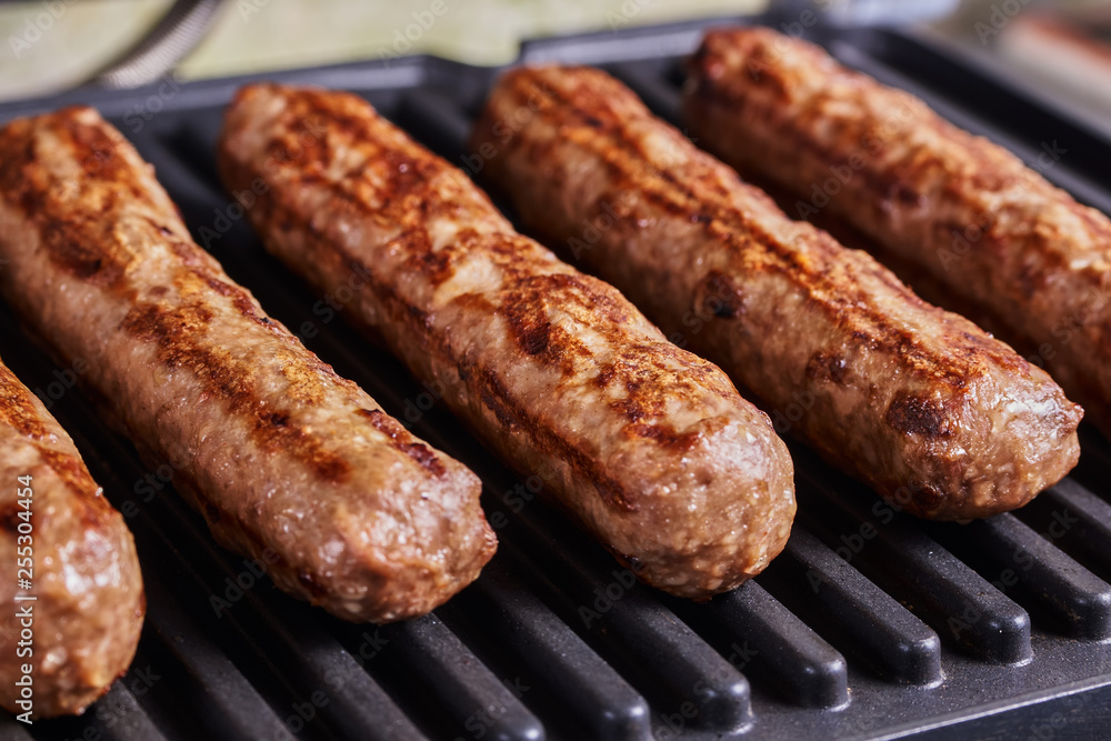 Serbian cevapi, cevapcici, Balkan minced meat kebab. Sausages cooking to grill. Close-up