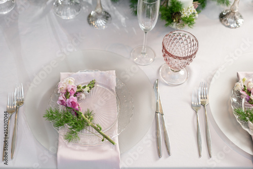 Closeup Table setting with plates and tableware, adorned with flowers. Floral decoration for wedding ceremony romance dining. Wedding banquet , festive decor. Concept of service and catering.