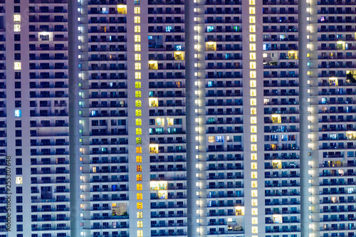 Tall residential highrise with apartment windows lit at night.  Individuality in big city living.  Condos for sale and rent.