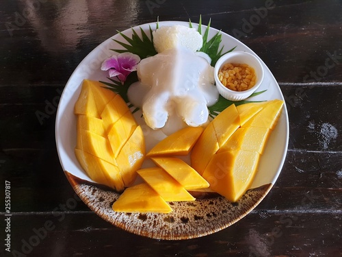 Top view of Thai mango sticky rice topped with coconut cream on wooden table, This food is most popular Thai derrest, Kao neaw ma moung is Thai traditional photo