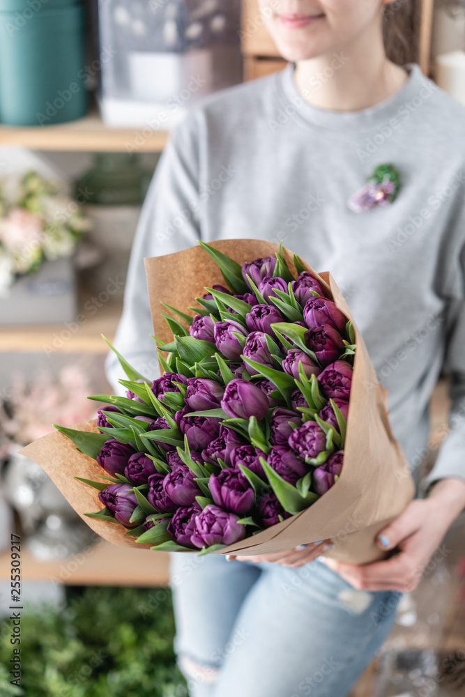 Young beautiful woman holding a spring bouquet of purple tulips in her hand. Bunch of fresh cut spring flowers in female hands Young beautiful woman holding a spring bouquet of purple tulips in her hand. Bunch of fresh cut spring flowers in female hands