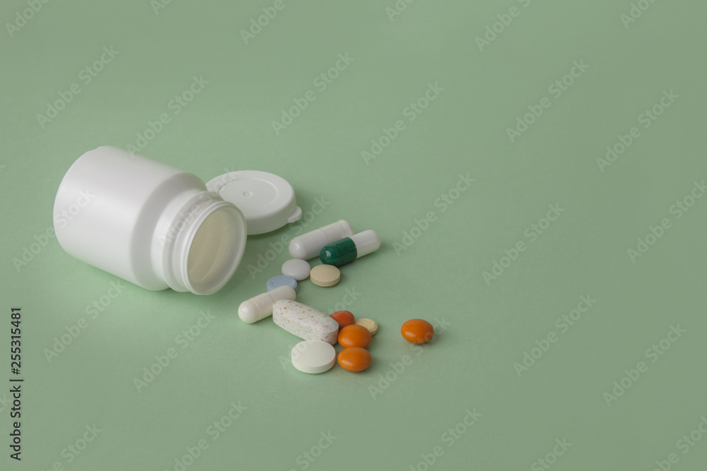 Pills, tablets and capsules and a bottle on a green background. Copy space for text. Pills, tablets and capsules and a bottle on a green background. Copy space for text.