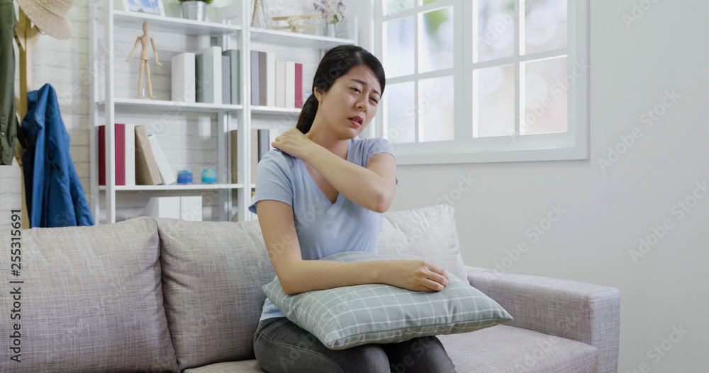 Attractive Asian female touching neck and shoulder in pain. Young housewife woman stretching body healthcare and medical painful concept. illness lady massage back ache sitting on couch resting. Attractive Asian female touching neck and shoulder in pain. Young housewife woman stretching body healthcare and medical painful concept. illness lady massage back ache sitting on couch resting.