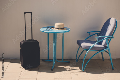 Suitcase  hat  sunglasses on the outdoor cafe table. Travel summer vacation concept