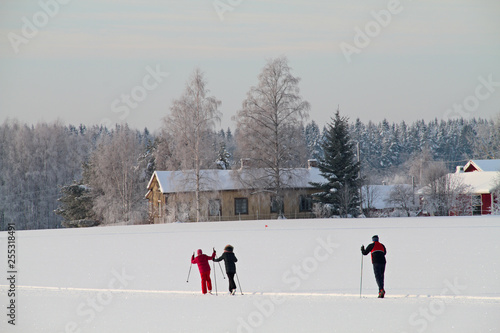 A family skiing together in a snowy white field on a cold day