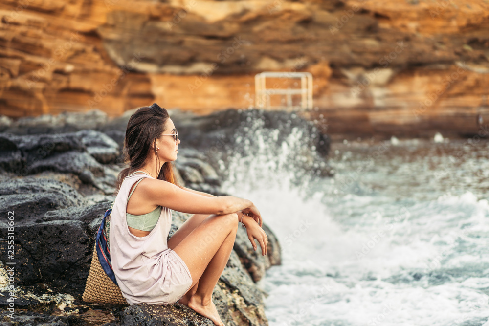 Pretty long hair brunette tourist girl relaxing on the stones near sea. Pretty long hair brunette tourist girl relaxing on the stones near sea.