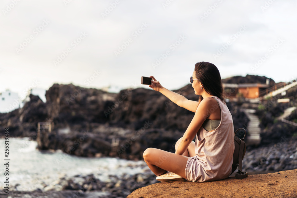 Pretty long hair brunette tourist girl relaxing on the stones near sea. Pretty long hair brunette tourist girl relaxing on the stones near sea.