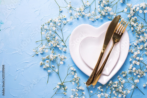 Plates in form of hearts, golden knife and fork and  fresh white gypsofila  flowers photo