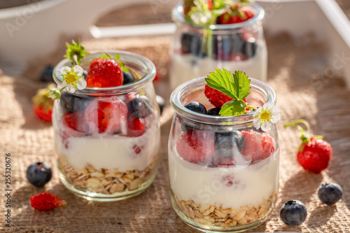 Tasty granola in jar with yoghurt and berries