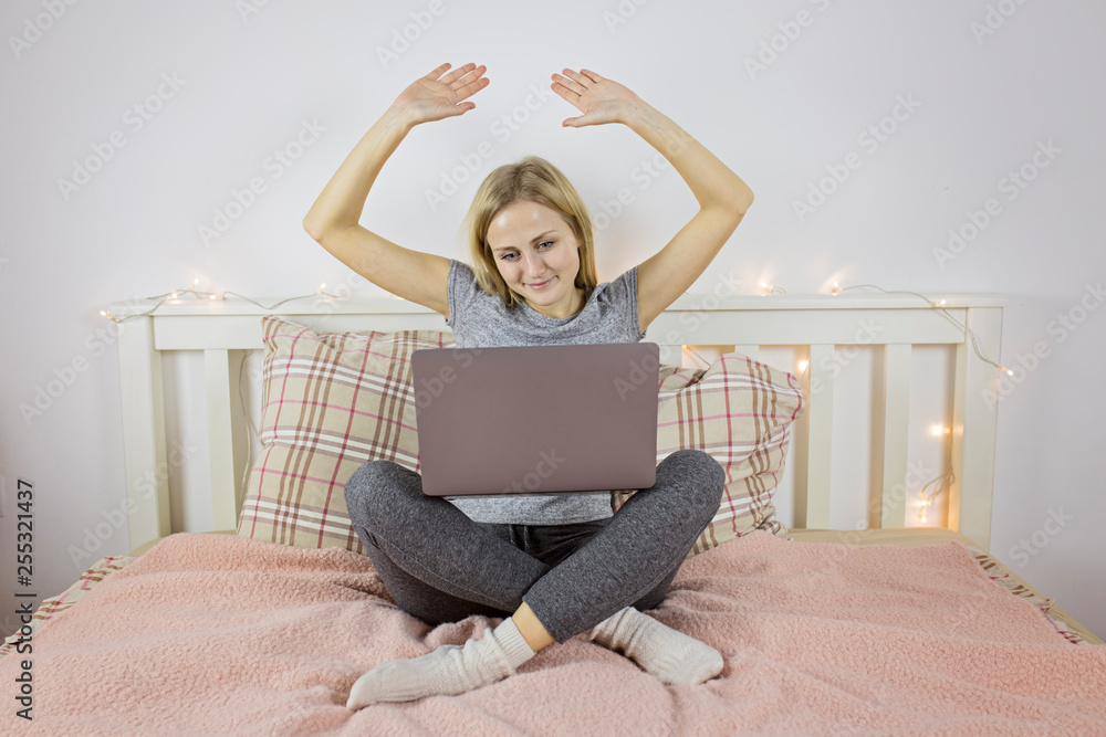 A girl with a contented face raised her hands up, working behind a laptop A girl with a contented face raised her hands up, working behind a laptop
