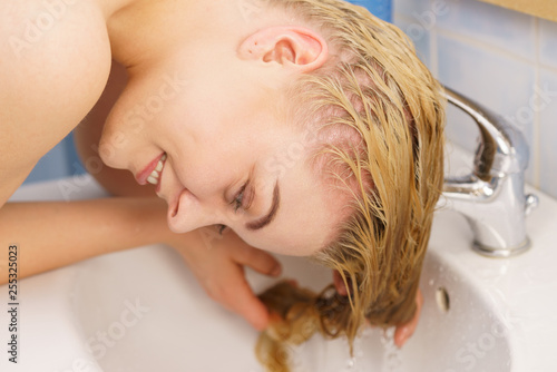 Woman washing hair in bathroom sink