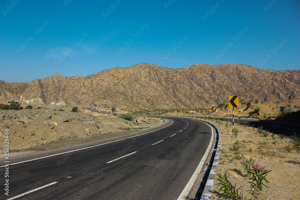 Mount Abu scenic road view with asphalt road and road signs, with mountain view and blue sky background.