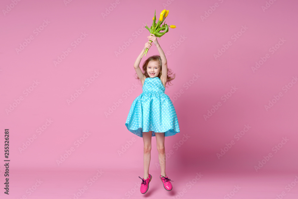 Cheerful girl with a bouquet of yellow tulips on a pink background. Holidays, fashion and red concept.