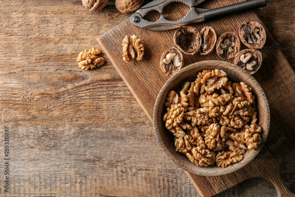 Bowl with tasty walnuts on wooden table