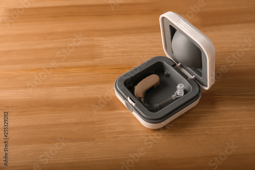 Box with hearing aid on wooden table