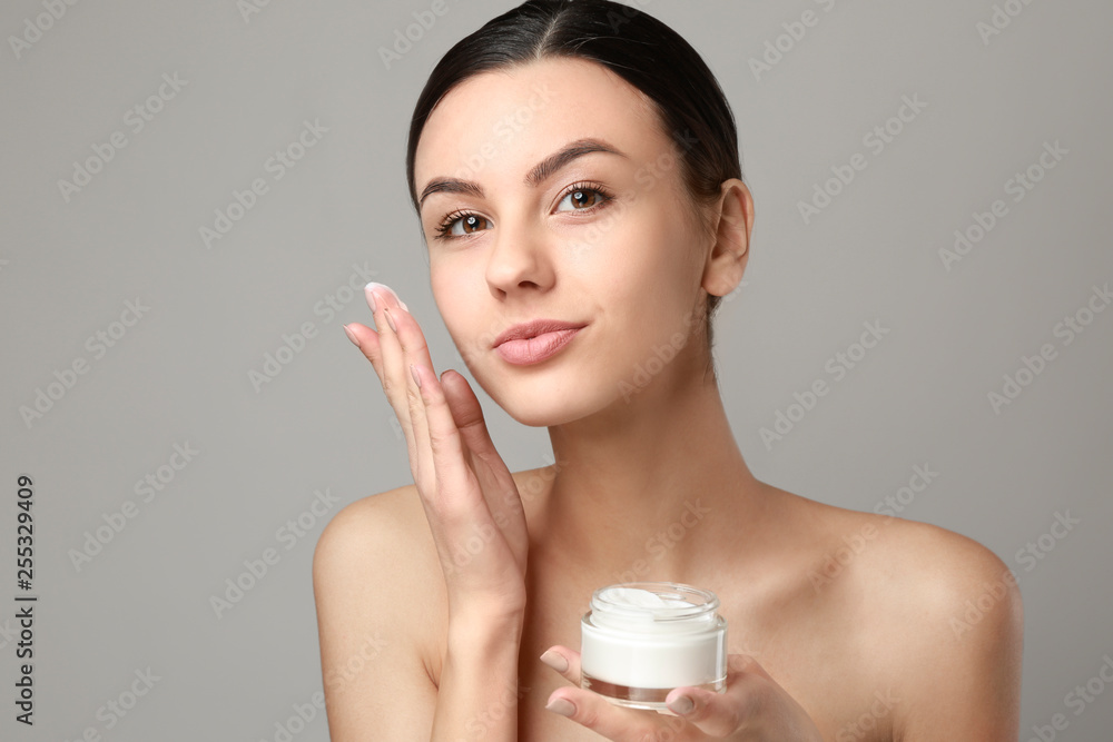 Portrait of beautiful woman with cream for healthy skin on grey background Portrait of beautiful woman with cream for healthy skin on grey background
