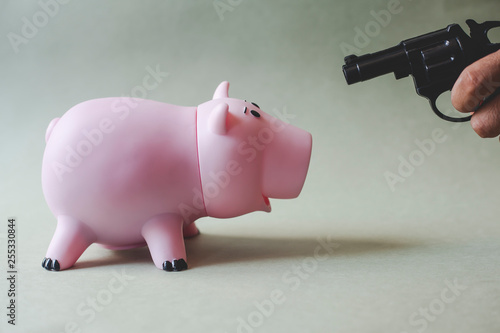pink piggy bank and hand with gun