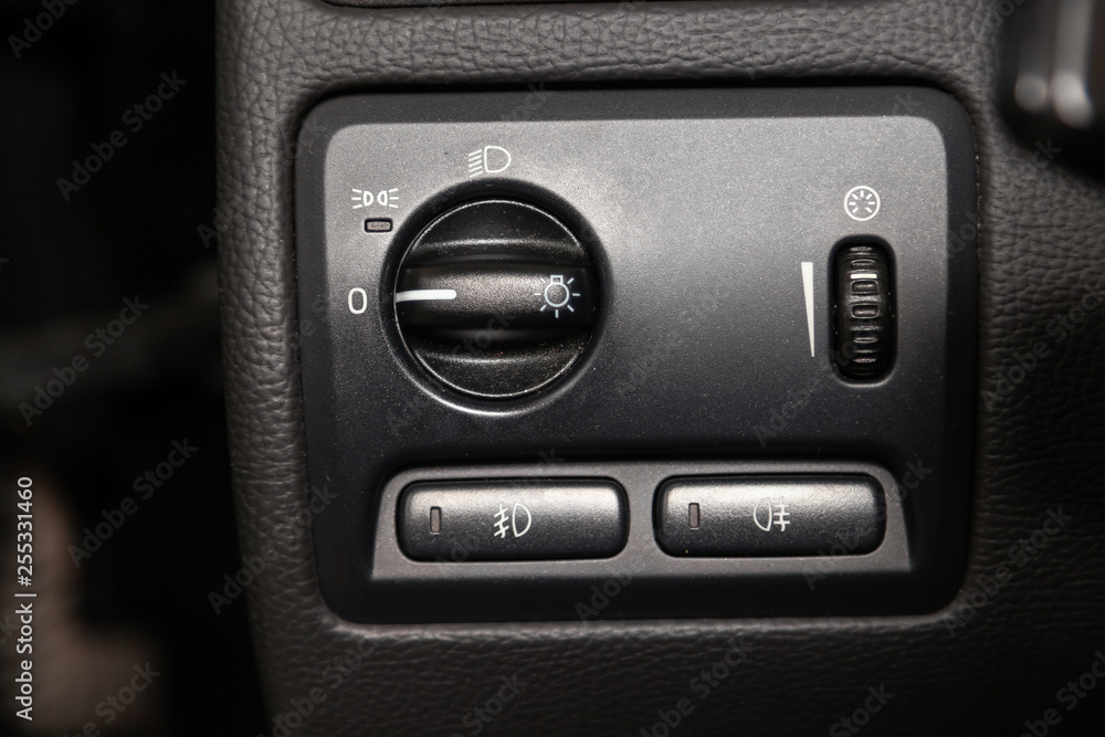 Interior view with headlamp and fog button switch of black car stands in the washing box waiting for repair in auto service