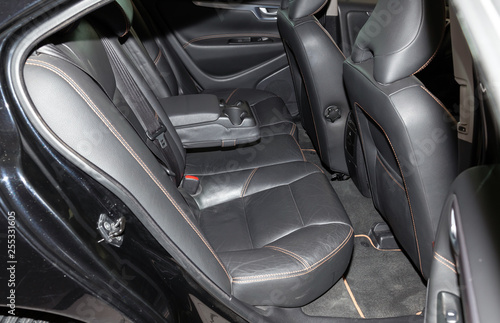 Clean after washing the rear passenger seats of matte black genuine leather inside the interior of an expensive sedan, preparation before selling the car. © Aleksandr Kondratov
