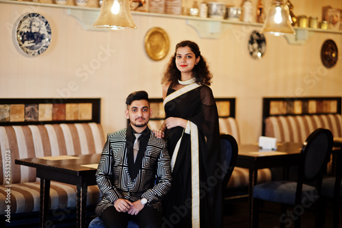 Lovely indian couple in love, wear at saree and elegant suit, posed on restaurant.
