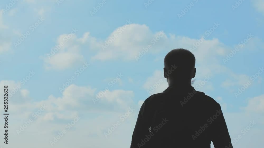 Silhouette of a young man watching the take-off of an airplane against a blue sky. Silhouette of a young man watching the take-off of an airplane against a blue sky.