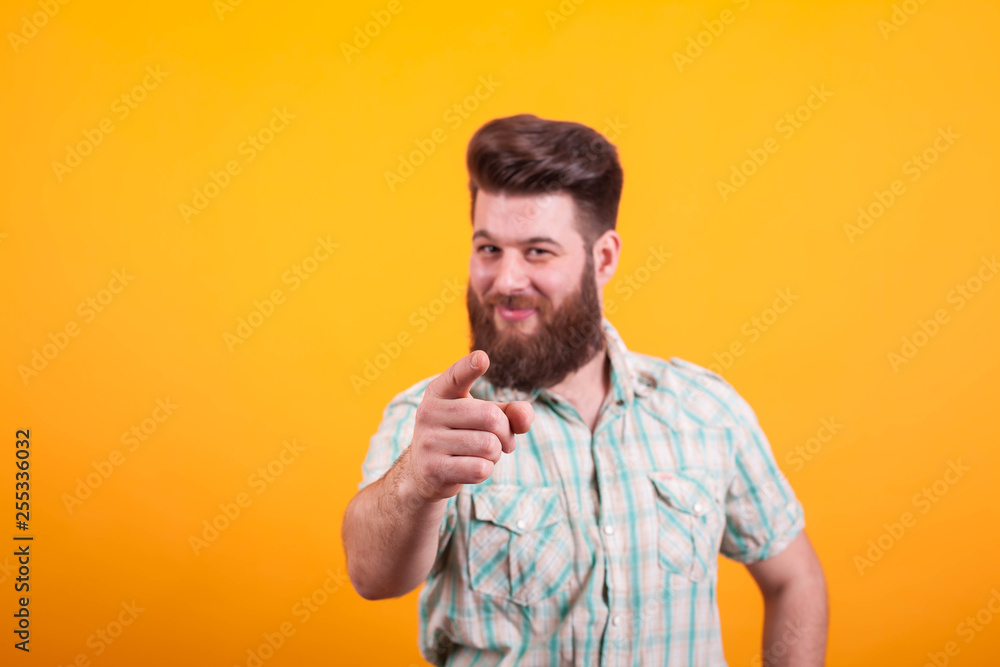 Handsome man with hand in focu pointing at the camera over yellow background Handsome man with hand in focu pointing at the camera over yellow background