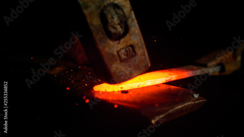 фотографія MACRO, DOF: Metalworker forging a glowing hot piece of metal into a knife blade