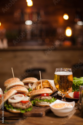 Tasty different burgers and a glass of cold beer on wooden table