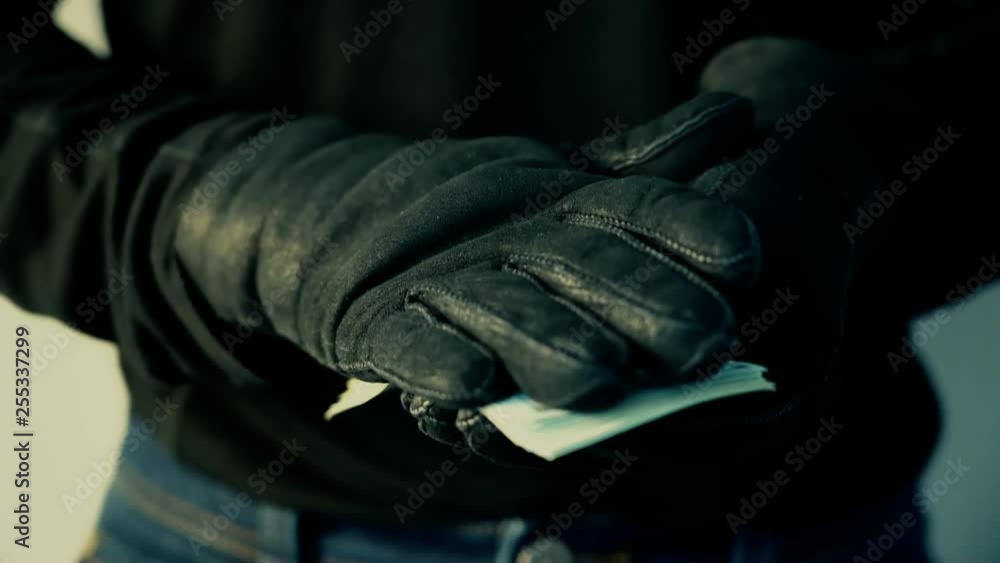 Man in black gloves holding pile of money, crime concept Man in black gloves holding pile of money, crime concept