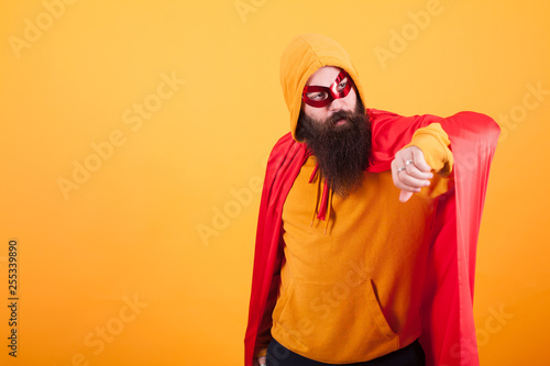 Hipster with long beard dressed in superhero costume looking away over yellow background © DC Studio