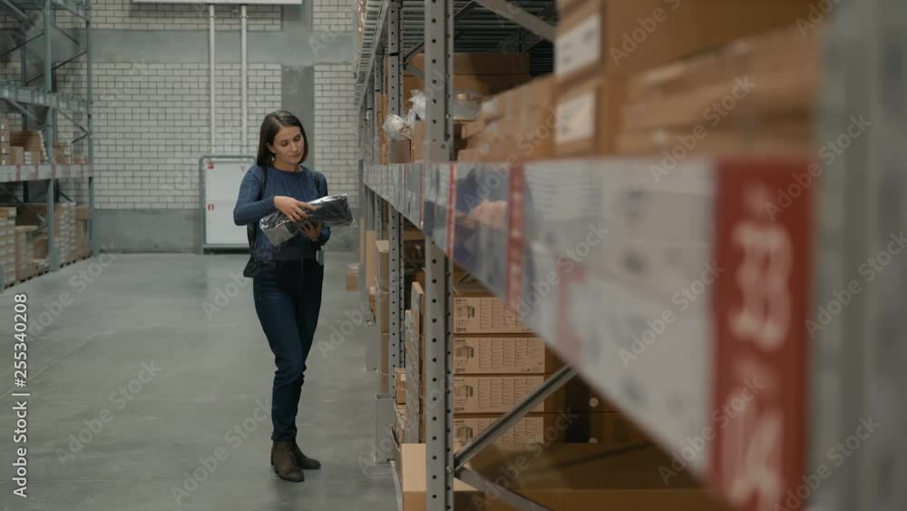 Young Caucasian woman choosing goods in shop warehouse. Young Caucasian woman choosing goods in shop warehouse.