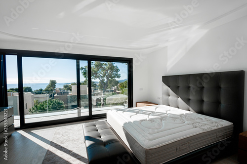 Minimalistic style bedroom in brown and beige tones with new mattress.