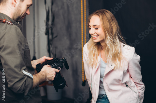 Photographer is showing to a charming girl photos on camera.close up photo.man working with a client , job, profession photo